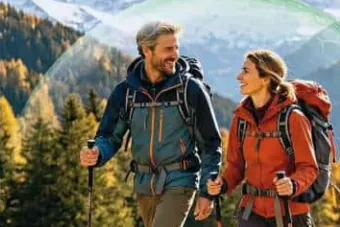 Two hikers with backpacks and trekking poles on a mountain trail in autumn
